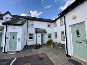 a row of white houses with green doors at 8 Howrahs Court, Keswick in Keswick