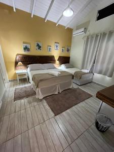 a bedroom with two beds in a room with a table at Hospedaria Gengibre in Barra Velha