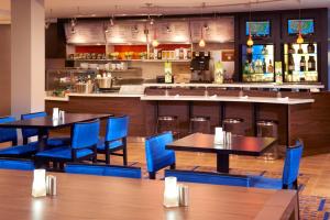 a restaurant with tables and blue chairs and a bar at Courtyard Toledo Rossford/Perrysburg in Rossford