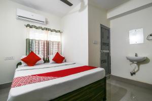 een slaapkamer met een bed met rode kussens en een wastafel bij OYO Flagship Hotel Lokenath in Jamshedpur