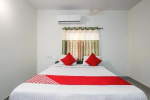 1 dormitorio con 1 cama grande con almohadas rojas en OYO Flagship Hotel Lokenath en Jamshedpur