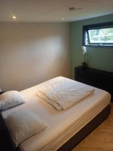 un letto con lenzuola e cuscini bianchi in una camera da letto di Vakantiechalet Tip 30 op vakantiepark de Heische Tip a Zeeland