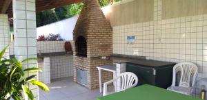 una cocina al aire libre con horno de ladrillo, mesas y sillas. en A Bela Casa da Ilha, na Ilha de Vera Cruz, Coroa, 300m da praia! en Salvador