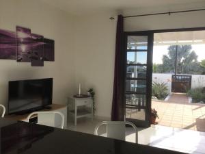 a living room with a television and a sliding glass door at Natural y sano: Charco del Palo in Charco del Palo