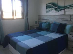 uma cama azul e branca num quarto com uma janela em Natural y sano: Charco del Palo em Charco del Palo