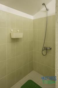 y baño de azulejos verdes con ducha y alfombra verde. en Casa do Merendário, en Praia da Vitória