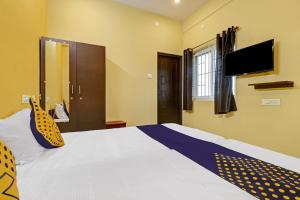 a bedroom with a bed with a tv on the wall at SPOT ON Kayal Residency in Coimbatore