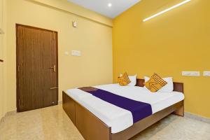 a bedroom with a bed with yellow walls and a door at SPOT ON Kayal Residency in Coimbatore