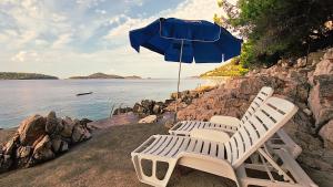 two lounge chairs and an umbrella on the beach at VillaV, seafront 2-story 4* apartment with great outdoors in Prizba
