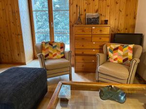 een woonkamer met 2 stoelen en een dressoir bij Au village d'Evolène, bel appartement avec terrasse in Evolène