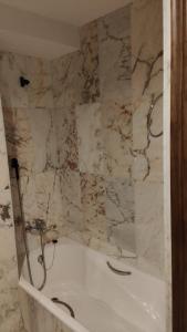 W łazience z marmurową ścianą znajduje się biała wanna. w obiekcie La canongia w mieście Segovia