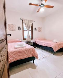 a bedroom with two beds and a ceiling fan at El Colonial Departamentos in Cafayate