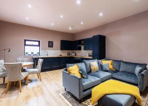 a living room with a blue couch and a kitchen at Beech Tree Lakes Lodges in Hatfield