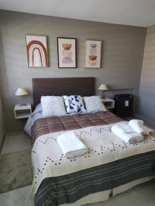 1 dormitorio con 1 cama grande y toallas. en M&M DEPARTAMENTO en El Calafate