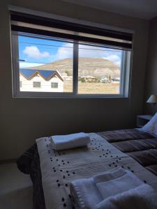 1 dormitorio con cama y ventana grande en M&M DEPARTAMENTO en El Calafate