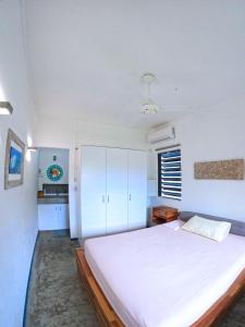 a bedroom with a large white bed and a kitchen at Cozy house for Kite & windsurfers (Le Morne) in Le Morne