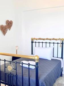 1 dormitorio con 1 cama con marco de metal y un corazón en la pared en Petalou House en Imerovigli