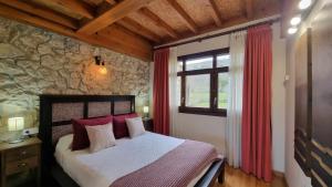 ein Schlafzimmer mit einem Bett und einer Steinwand in der Unterkunft Casa Vacacional Los Gemelos in San Roque del Acebal