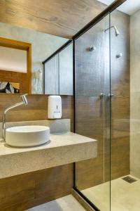 La salle de bains est pourvue d'un lavabo et d'une douche en verre. dans l'établissement Bravo Pousada Design, à Cabo Frio