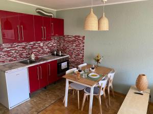 a kitchen with red cabinets and a wooden table with chairs at Apartment Vita in Bovec