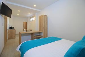 a bedroom with a bed and a desk with a television at Apart Hotel Casa Blanca in Cuenca