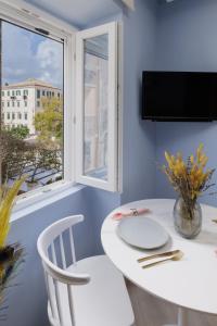 una mesa y sillas blancas en una habitación con ventana en Old Town Hall Apartment en Corfú