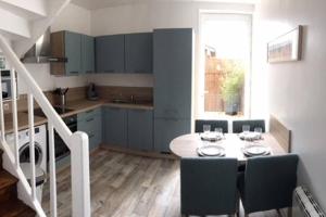 a kitchen with a table and chairs and a kitchen with a staircase at Le Dhoni in Fécamp