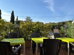 2 gelbe Tische und Stühle auf einer Terrasse in der Unterkunft Hotel & Appartements Punta e Mare in Cargèse