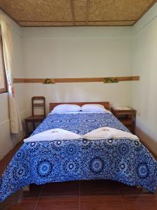 a bedroom with a bed with a blue and white comforter at La Ramada de Mama Elena in Oxapampa