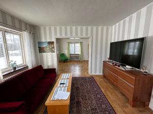 a living room with a couch and a flat screen tv at Ljungaverk Stor Lägenhet Med Öppen Spis in Ljungaverk