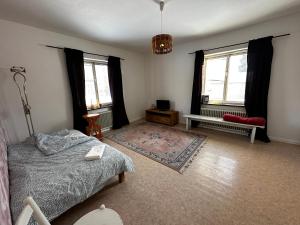 ein Schlafzimmer mit einem Bett und einer Bank sowie zwei Fenstern in der Unterkunft Ljungaverk Stor Lägenhet Med Öppen Spis in Ljungaverk