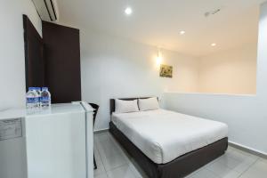 Dormitorio pequeño con cama y botellas de agua en Hollitel Hotel, en Melaka