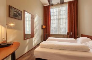 1 Schlafzimmer mit 2 Betten, einem Schreibtisch und einem Fenster in der Unterkunft A-Train Hotel in Amsterdam