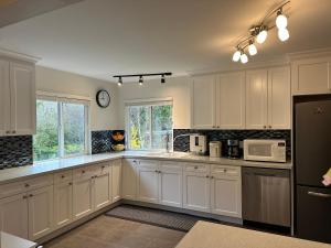 a kitchen with white cabinets and a black refrigerator at Aileen Full House in Delta