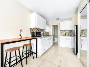 a kitchen with white cabinets and a counter and stools at The Oasis in Hollywood