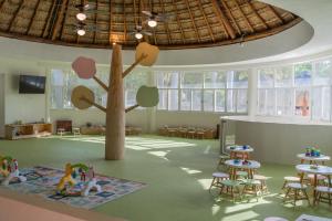 a room with a tree and tables and chairs at Iberostar Waves Paraíso del Mar - All Inclusive in Puerto Morelos