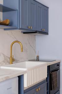a kitchen with blue cabinets and a sink at Old Town Hall Apartment in Corfu Town