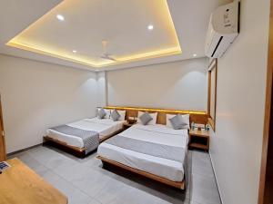 sypialnia z dwoma łóżkami i telewizorem w obiekcie HOTEL OM w mieście Somnath
