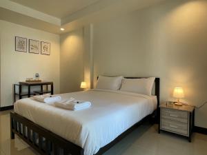 1 dormitorio con 1 cama blanca grande y 2 mesas en Ivory House Sriracha en Si Racha