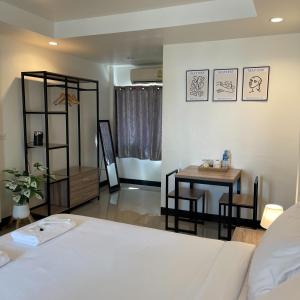 a bedroom with a white bed and a table and a table at Ivory House Sriracha in Si Racha