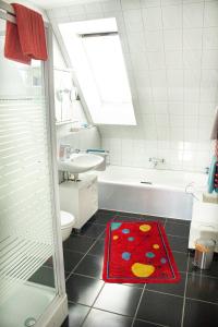 Baño con alfombra roja en el suelo en Ferienwohnung Welcome en Telgte