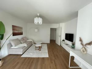 a white living room with a couch and a tv at Eckberg Apartment near City Centre & Nature in Baden-Baden