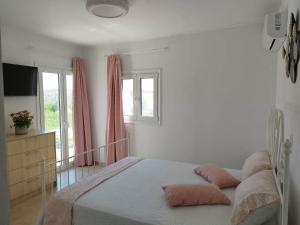 Un dormitorio con una cama con almohadas rosas. en Emmanuela House with garden & sea view - Triopetra, en Triopetra