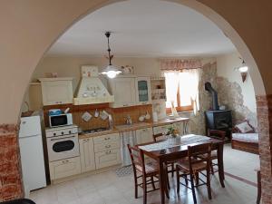 una cocina con mesa y sillas y una cocina con electrodomésticos blancos. en Belvedere Apartment en SantʼAlfio