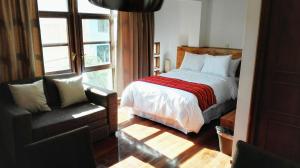 1 dormitorio con 1 cama, 1 silla y 1 ventana en La Aurora, en Huaraz
