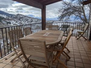 - une table et des chaises en bois sur un balcon avec des montagnes enneigées dans l'établissement Atalaya - Montserrat Figueras - Gîte pour 8 personnes - 4 chambres en suite - Piscine, à Llo