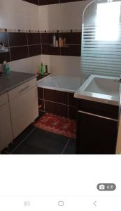 ein Badezimmer mit einer Badewanne und einem Waschbecken in der Unterkunft Maison de Vacances in Locronan