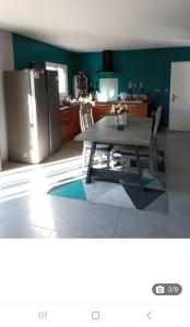 eine Küche mit einem Tisch und einem Kühlschrank aus Edelstahl in der Unterkunft Maison de Vacances in Locronan