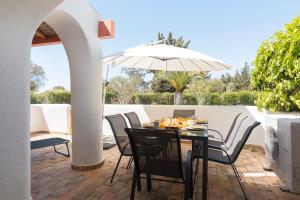 a table with chairs and an umbrella on a patio at Aldeia do Golfe - Private condominium by HD in Vilamoura