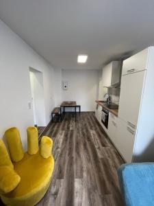 a living room with a yellow couch and a kitchen at Sam Apartments LU/Oppau in Ludwigshafen am Rhein